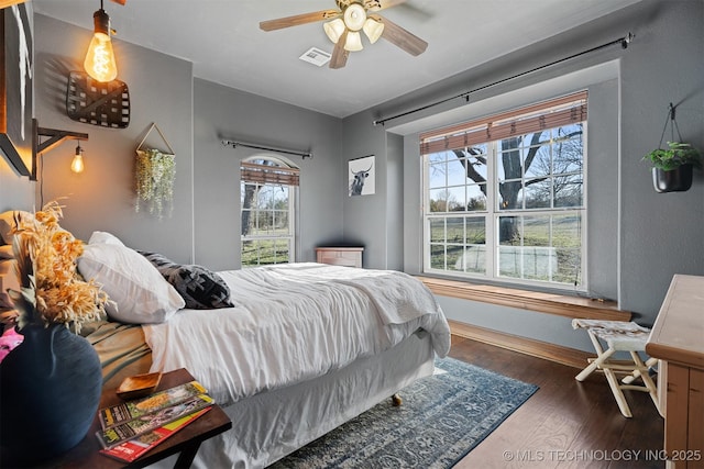 bedroom with visible vents, ceiling fan, baseboards, and hardwood / wood-style floors