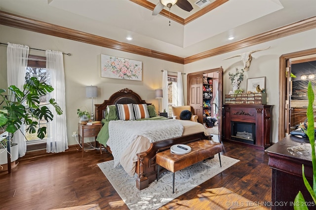 bedroom featuring dark wood finished floors, crown molding, a fireplace, and visible vents