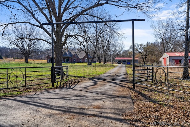 view of street with aphalt driveway, a gated entry, a rural view, and a gate