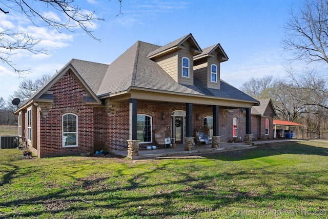 view of front facade with a front yard, central air condition unit, brick siding, and a shingled roof