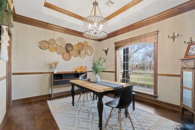 dining room featuring visible vents, a tray ceiling, an inviting chandelier, and hardwood / wood-style floors