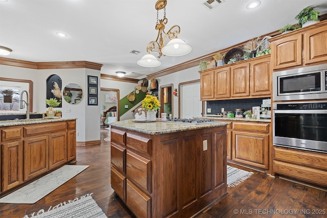 kitchen featuring visible vents, a sink, a center island, appliances with stainless steel finishes, and crown molding