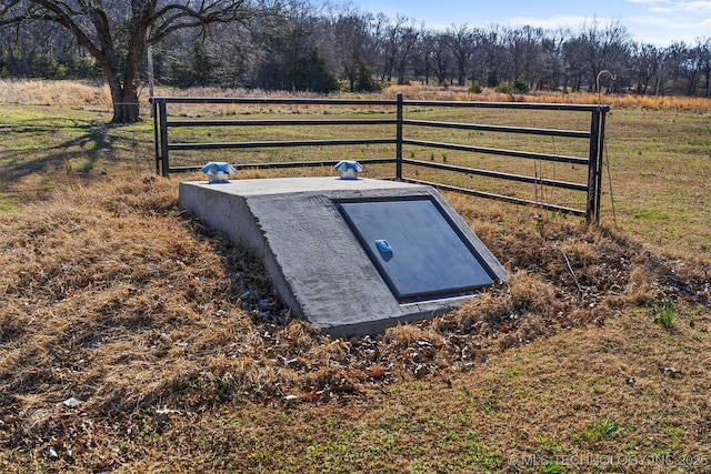 entry to storm shelter featuring a rural view and fence