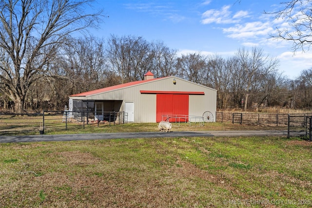 view of pole building featuring aphalt driveway, a yard, and fence