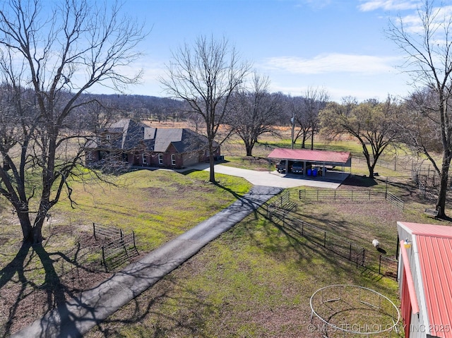 view of yard with an outbuilding, driveway, fence, a rural view, and a carport