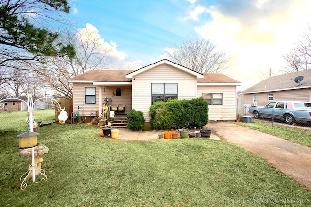 view of front facade featuring concrete driveway, a front lawn, and fence