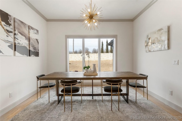 dining area with crown molding, baseboards, light wood finished floors, and a chandelier