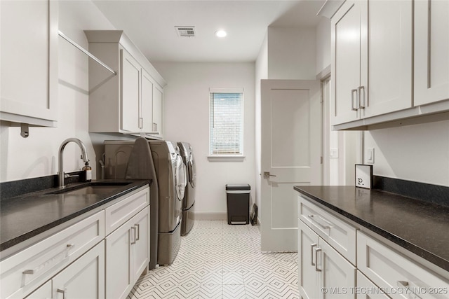 laundry area featuring visible vents, baseboards, cabinet space, independent washer and dryer, and a sink