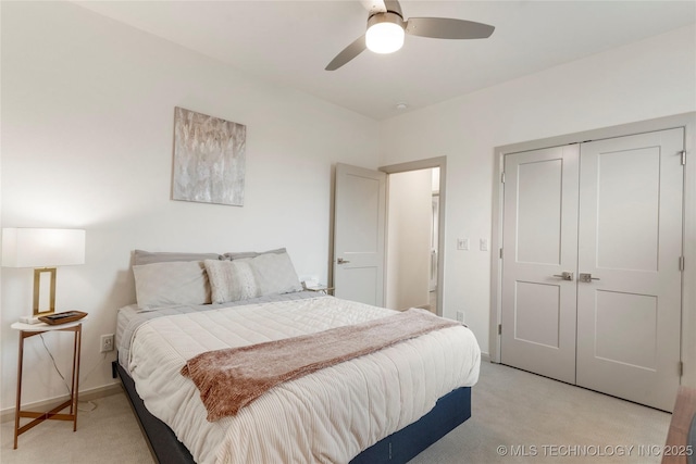 bedroom featuring a ceiling fan, light colored carpet, a closet, and baseboards