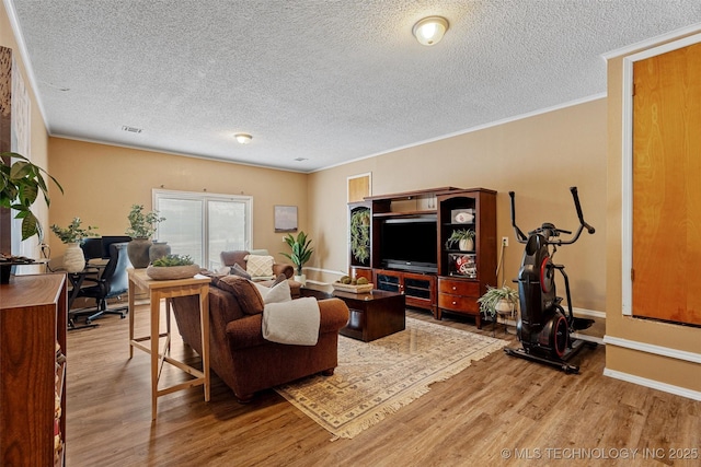 living area with visible vents, ornamental molding, a textured ceiling, wood finished floors, and baseboards