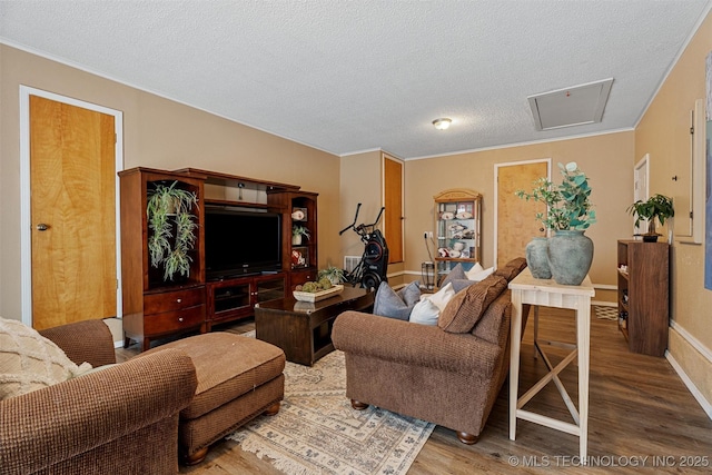 living area with a textured ceiling, crown molding, baseboards, and wood finished floors