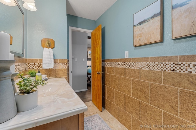 bathroom featuring tile patterned flooring, a wainscoted wall, tile walls, and vanity