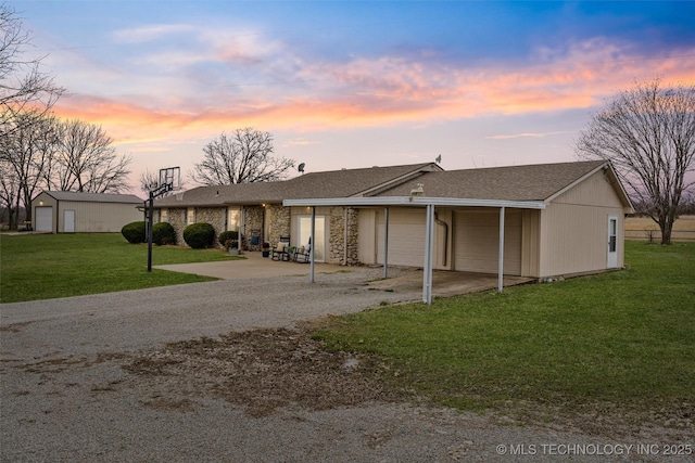 view of front of home with a front yard, gravel driveway, an attached garage, a shingled roof, and stone siding