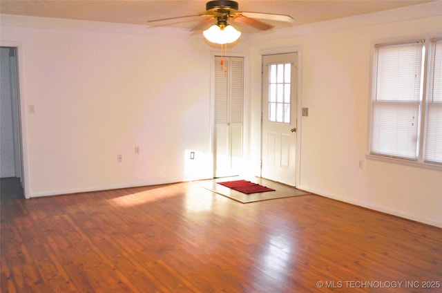 interior space featuring ceiling fan, baseboards, and wood finished floors