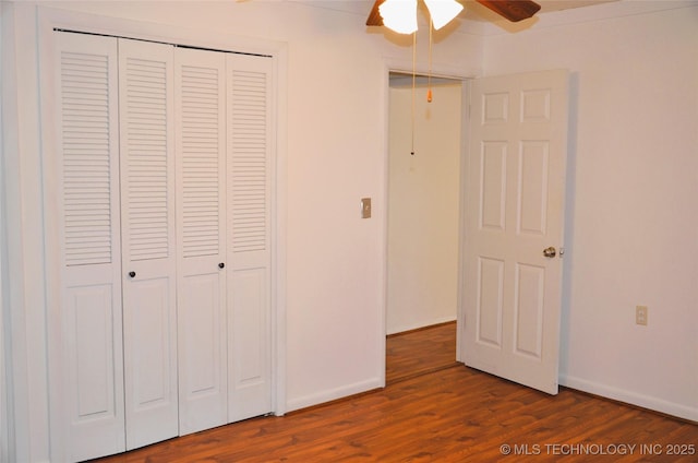 unfurnished bedroom featuring a closet, baseboards, wood finished floors, and a ceiling fan