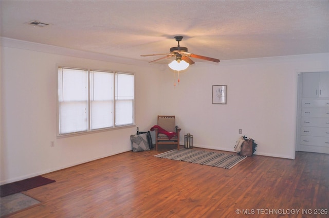 interior space with visible vents, crown molding, ceiling fan, and wood finished floors