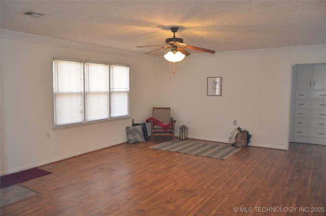 unfurnished room featuring a ceiling fan, wood finished floors, visible vents, and ornamental molding