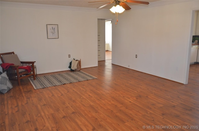 living area with ornamental molding, wood finished floors, baseboards, and ceiling fan