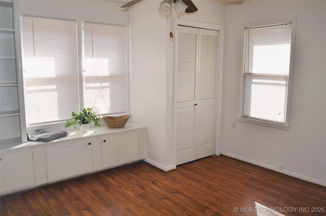 unfurnished bedroom with dark wood-style floors, a closet, and baseboards