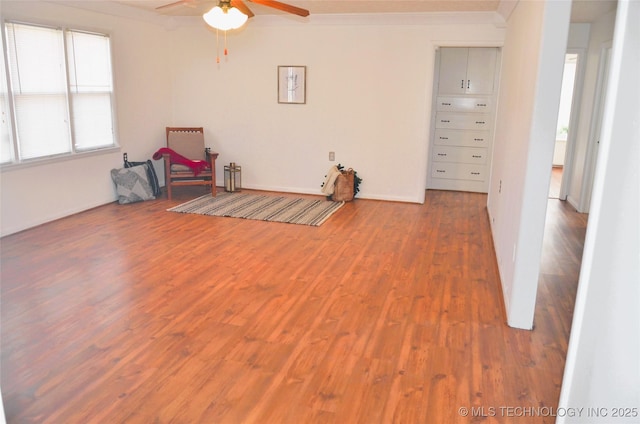 interior space with wood finished floors, a ceiling fan, and crown molding