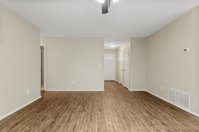 unfurnished room featuring a ceiling fan, wood finished floors, visible vents, and baseboards