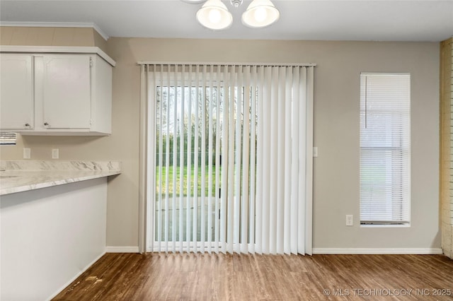 unfurnished dining area with baseboards, a notable chandelier, and wood finished floors