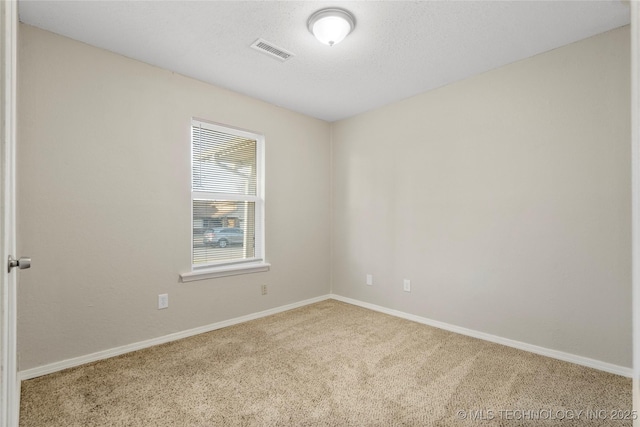 unfurnished room with a textured ceiling, carpet, visible vents, and baseboards