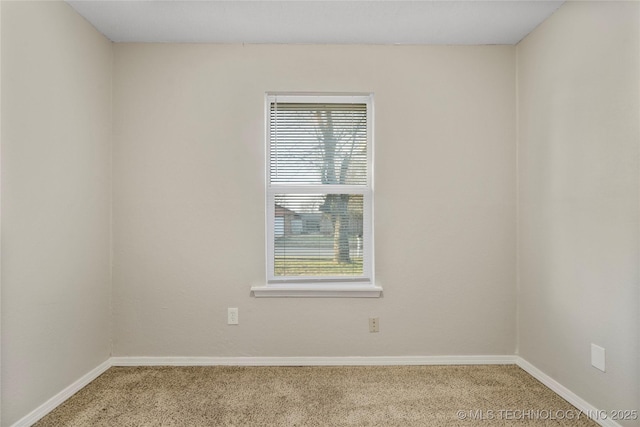 empty room featuring light colored carpet and baseboards