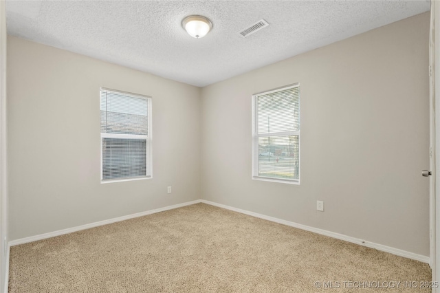 carpeted empty room with visible vents, a textured ceiling, and baseboards