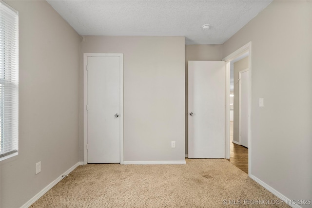 unfurnished bedroom featuring baseboards, a textured ceiling, and carpet flooring