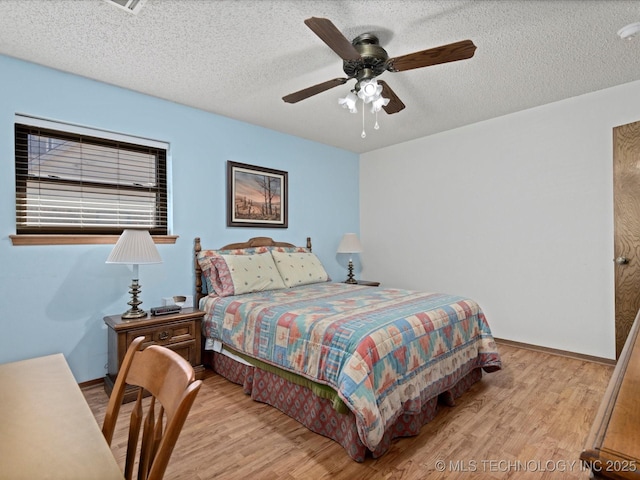 bedroom featuring a textured ceiling, baseboards, and wood finished floors