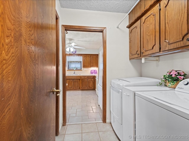 clothes washing area with ceiling fan, washer and clothes dryer, cabinet space, a textured ceiling, and a sink