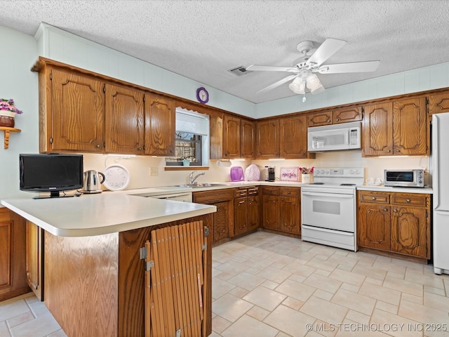 kitchen featuring white appliances, a peninsula, brown cabinets, and light countertops