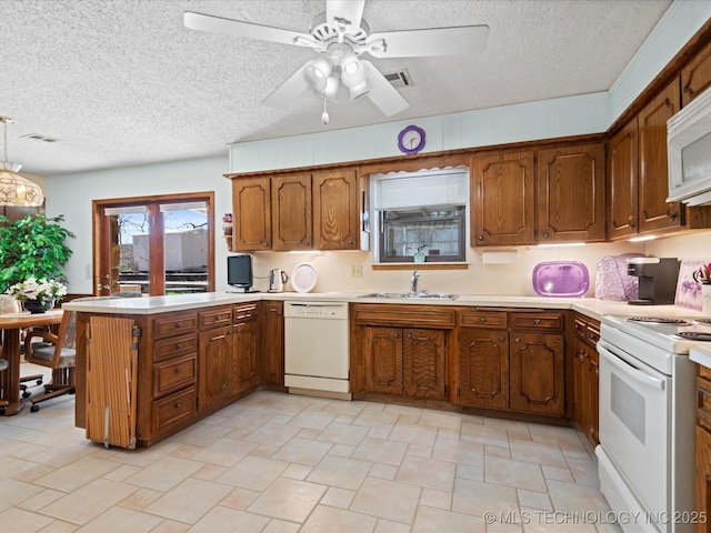 kitchen featuring white appliances, brown cabinetry, a peninsula, and light countertops