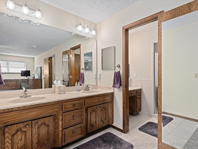 full bath featuring double vanity, a textured ceiling, and a sink