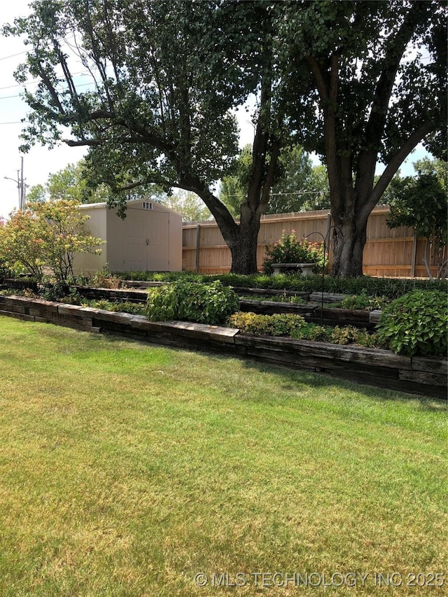 view of yard featuring an outdoor structure, a vegetable garden, a storage unit, and fence