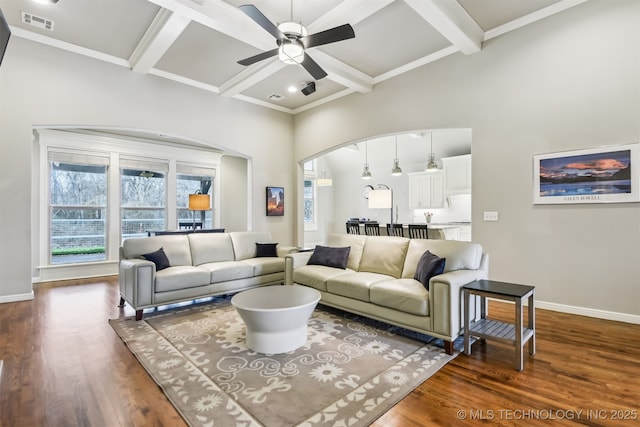 living room featuring dark wood-type flooring, arched walkways, a ceiling fan, and baseboards