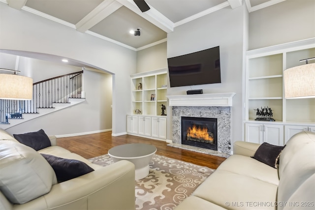 living room with a high end fireplace, wood finished floors, crown molding, and stairs