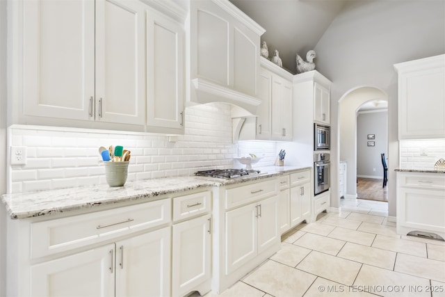 kitchen with arched walkways, white cabinets, stainless steel appliances, and light tile patterned flooring