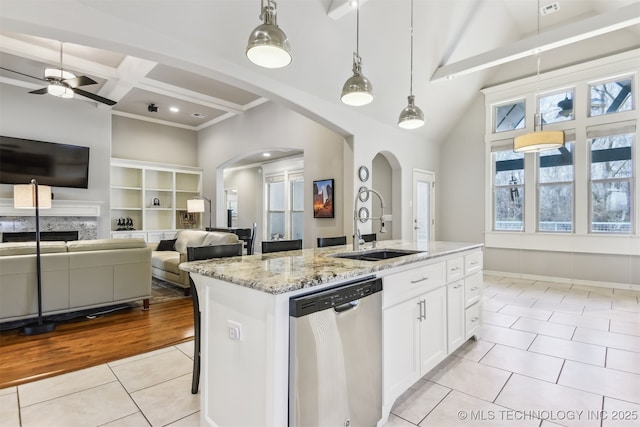 kitchen with stainless steel dishwasher, a sink, light tile patterned floors, arched walkways, and beamed ceiling