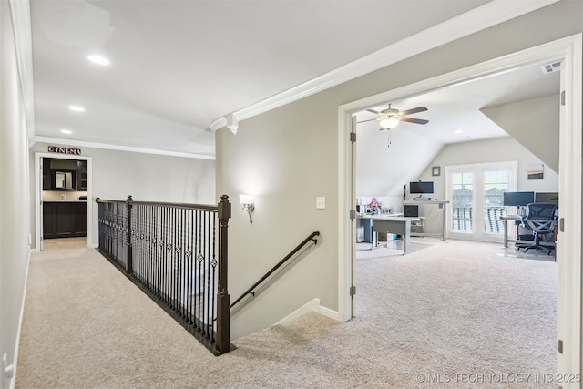 corridor with vaulted ceiling, carpet floors, ornamental molding, and an upstairs landing