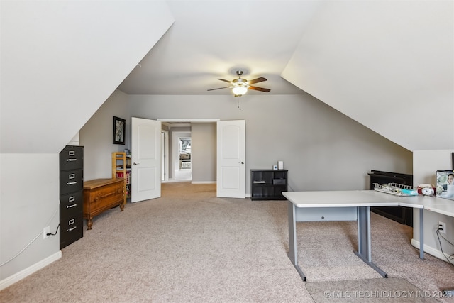 office area featuring baseboards, light carpet, lofted ceiling, and a ceiling fan