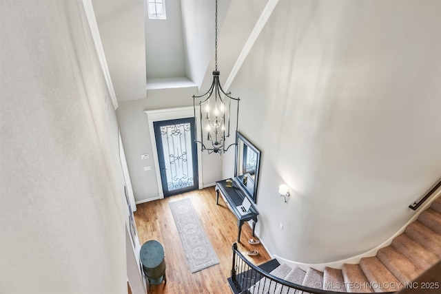foyer entrance featuring stairway, wood finished floors, an inviting chandelier, a wealth of natural light, and a towering ceiling