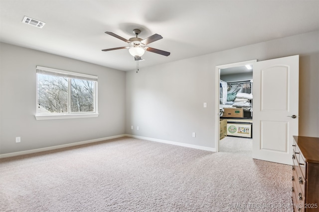 carpeted spare room featuring visible vents, baseboards, and ceiling fan