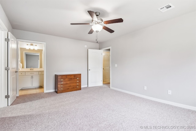 unfurnished bedroom featuring a ceiling fan, ensuite bathroom, light carpet, baseboards, and visible vents