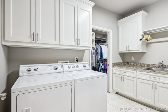 laundry area featuring light tile patterned flooring, cabinet space, independent washer and dryer, and a sink