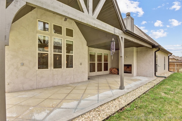 back of house with fence, a patio, and stucco siding