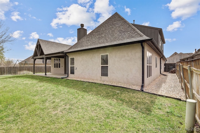 rear view of house with stucco siding, a patio, a lawn, and roof with shingles