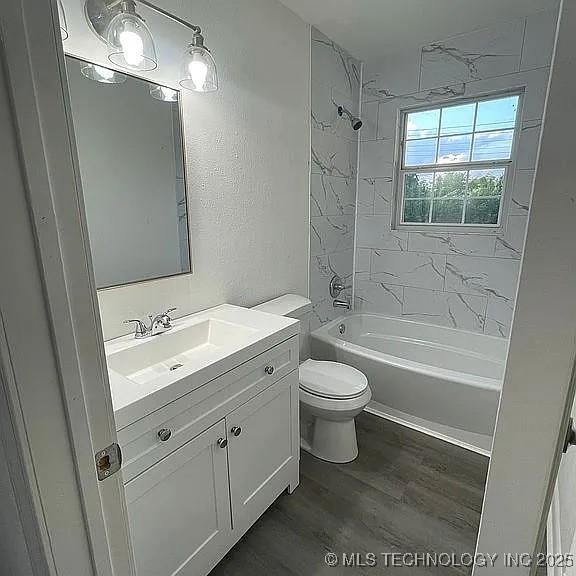 full bathroom featuring vanity, wood finished floors, shower / tub combination, toilet, and a textured wall