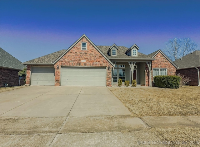 view of front facade featuring a garage, brick siding, roof with shingles, and driveway